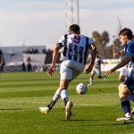 Players in action on the soccer field during an outdoor match under the bright sun.