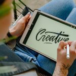 Person using stylus pen on tablet for digital lettering showing creativity in design.